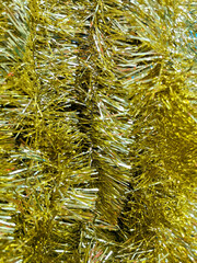 Christmas decor yellow tinsel blurred background, top view. New Year's background. Christmas background.