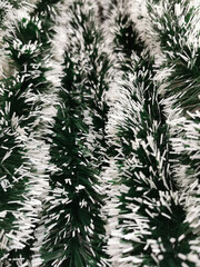 Christmas decor green tinsel blurred background, top view. New Year's background. Christmas background.