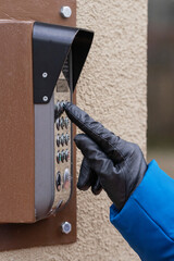 A female hand dials the code on the intercom.