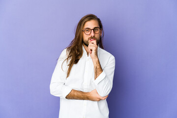 Young man with long hair look smiling happy and confident, touching chin with hand.