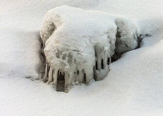 Icicles and frost on a snow-covered frozen river