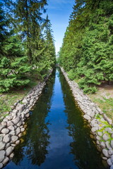 Obraz premium Summer landscape in a city Park with trees, grass, river, sky with clouds