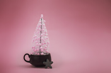 Christmas tree in coffee cup on pink background. Christmas and hew year minimalistic concept background.