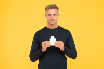 Apply fragrance on your skin. Handsome man hold perfume bottle yellow background. Mens grooming. Skin cosmetics. Cosmetic product. Skincare lotion. Shaving line. Aftershave cologne