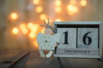Cube wooden calendar showing date on 16th December with Angel over bokeh background. Advent calendar, Christmas background, Copy space