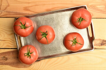 Ripe pink tomatoes, close-up, on a white wooden table.