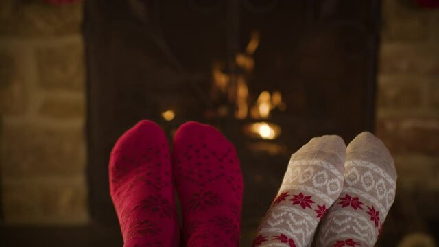 Close Up Shot of Couples Feet In Front of a Cosy Burning Fireplace