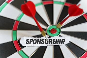 A piece of paper with the text is nailed to the target with a dart - SPONSORSHIP