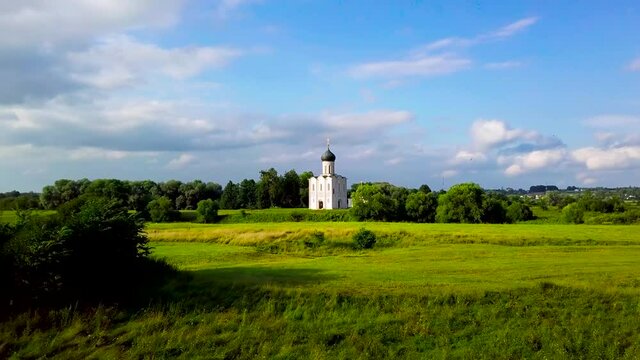 White Church on the hill. Summertime, daylight, green field, gree bushes. Church of interception of the holly virgin on the Nerl river. Russian Federation, Vladimir region, Bogolubovo.
