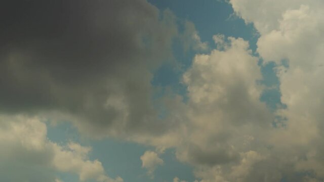 Thick white clouds float across the blue summer sky. Timelapse. Sunny.