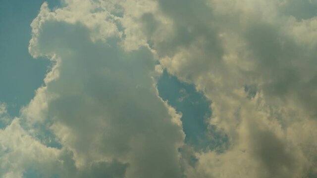 Thick white clouds float across the blue summer sky. Timelapse. Sunny.
