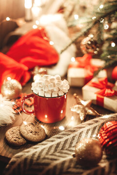 Christmas Red Mug With Cocoa And Marshmallows And Cookies On A Wooden Table. New Year's Still Life With A Christmas Tree, A Santa Hat And Festive Decorations.