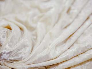 Macro photography of velvet in beige color. Textured ivory velour fabric with wavy shape to show structure. Nude wallpaper for fashion background atelier with copy space for text on the side.