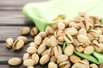 Tasty pistachios with green napkin on wooden table
