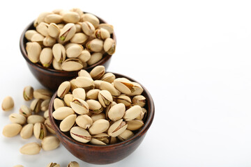 Tasty pistachios in bowls on white background