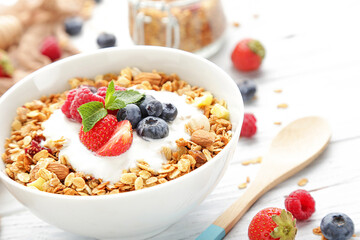 Tasty granola with fresh berries on white wooden background