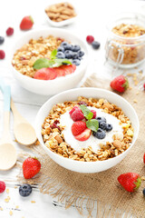Tasty granola with fresh berries on white wooden background