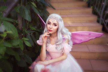 Young attractive girl dressed as fairy in green garden © kittyeastarea