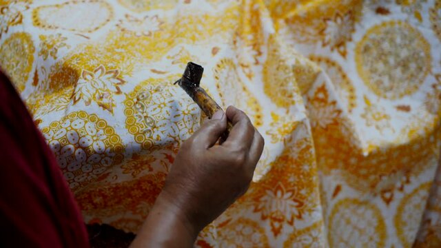 Indonesia December 2, 2020: Batik, Close Up hand and canting, making Batik Tulis Indonesia. Canting is a tool for drawing the texture on the fabric.

