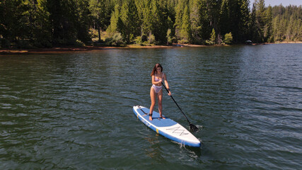 Fototapeta na wymiar The young lady paddling on the mountain lake