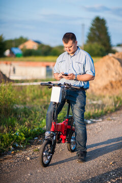 Male businessman with mobile phone on an electric bike.