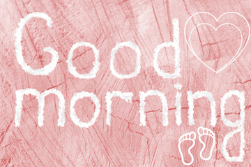 Good morning. The inscription good morning on a pink wooden background. Heart, footprints.