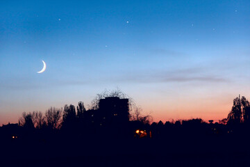 Evening sky with stars and Moon above city. Night town
