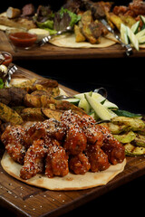 chicken in teriyaki sauce and sesame seeds on a board with reflection on a black background