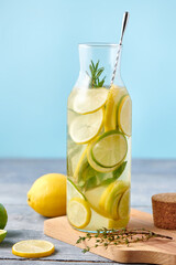 Fresh homemade lemonade with lime and mint and bar spoon in iced glass bottle on blue background