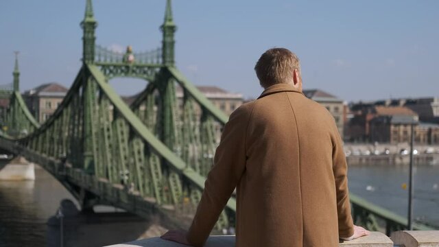 a man stands with his back and looks at the Liberty Bridge Budapest