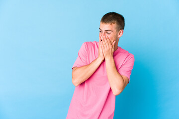 Young caucasian handsome man laughing about something, covering mouth with hands.