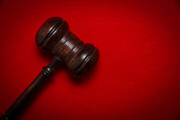 Wooden judge's gavel on a red background. The concept of issuing decisions, verdicts. Accusing and punishing criminals.