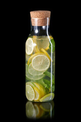 Fresh homemade lemonade with mint and ice in the glass bottle with cork isolated on black background