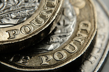 British one Pound coins on top of each other with word “Pound” in a main focus. Macro....
