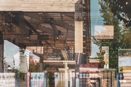 Blurred bookshelfs of bookstore with colorful books, reflections of street views of city streets in the glass showcase. Abstract background