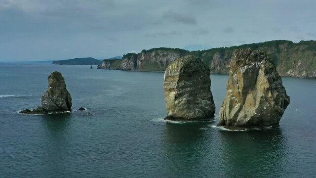 Aerial around view of Three brother rocks, Avacha bay, Kamchatka peninsula, Russia, 4k