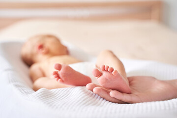 Newborn tiny legs. Sister holding little feet. Two people. Healthcare concept. Unrecognised modern...