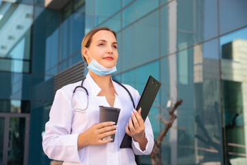 Young and attractive woman doctor with cup of tea in hand, enjoys relaxing lunch break. Side view...