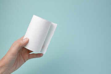 Roll of white toilet paper in a woman's hand on a dirty blue background. Toilet paper runs out. 
