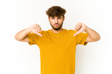 Young arab man on white background showing a dislike gesture, thumbs down. Disagreement concept.