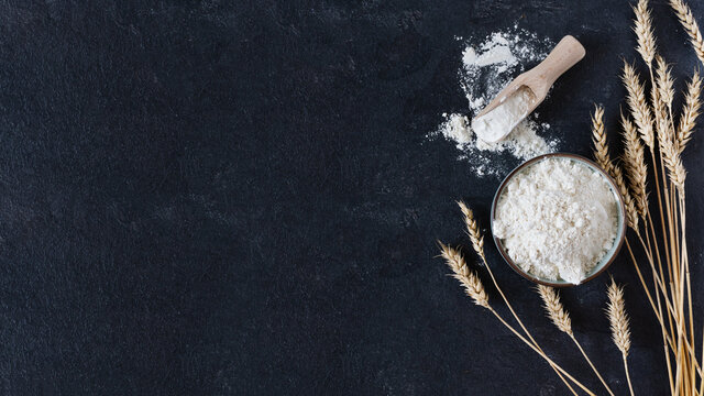 Bowl Of Wheat Flour Over Black Surface Top View. Baking Background.