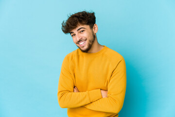 Young arab man on blue background laughing and having fun.