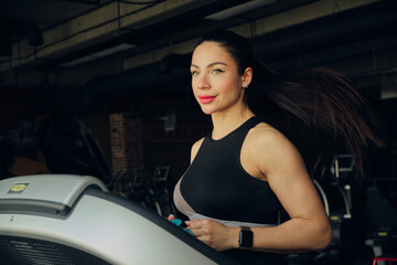 Fototapeta na wymiar Attractive young woman running on treadmill in sport gym