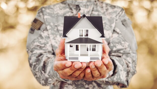 Soldier man holding a model of house