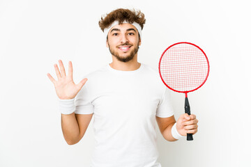 Young indian man playing badminton smiling cheerful showing number five with fingers.