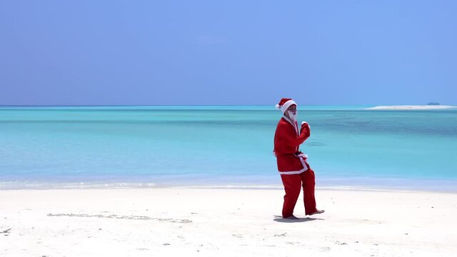 Santa Claus run and jump along beach and wag hands. Christmas vacation on islands