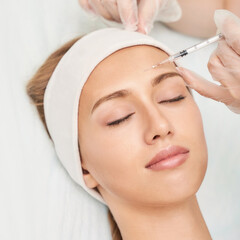 Forehead injection at spa salon. Doctor hands. Closeup. High quality. Pretty female patient. Beauty treatment. Healthy skin procedure. Young woman face. Light background. Plasmolifting rejuvenation