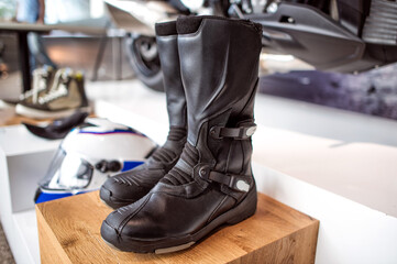 Biker's black leather boots on background of a motorcycle.