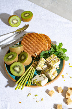 High angle view of kiwis, crackers, mint leaves and tahini halva on plate