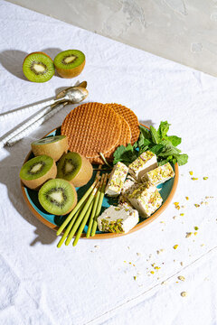 High angle view of kiwis, crackers, mint leaves and tahini halva on plate